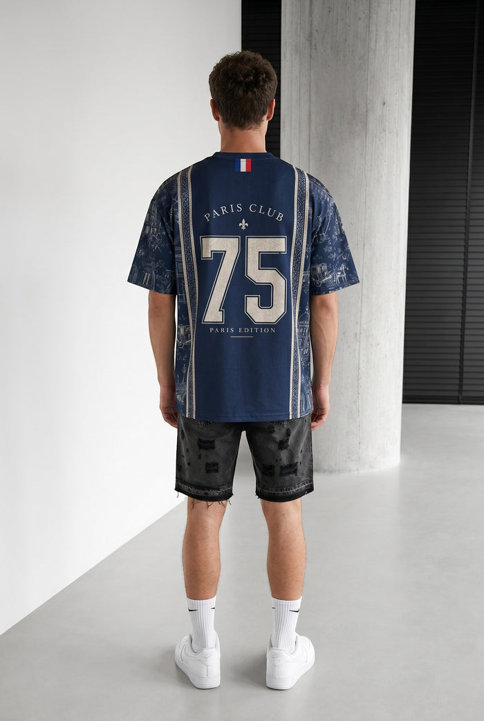 Homme portant un maillot bleu marine bonhomme avec le numéro 75 et des motifs parisiens au dos, coupe oversize.